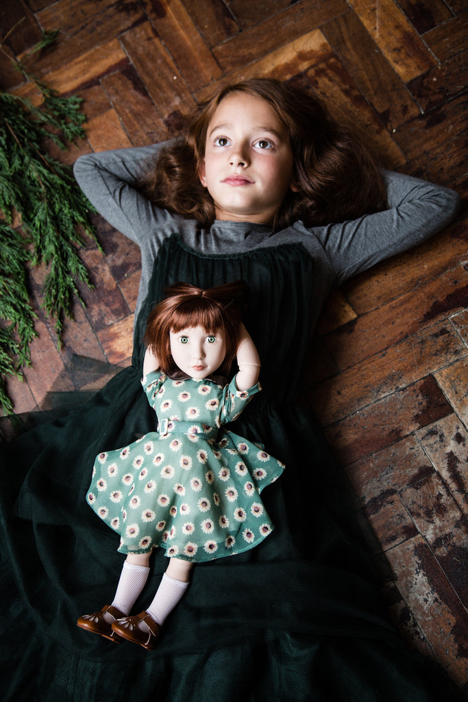 Girl lies on floor dreaming of adventure with her A Girl for All Time doll